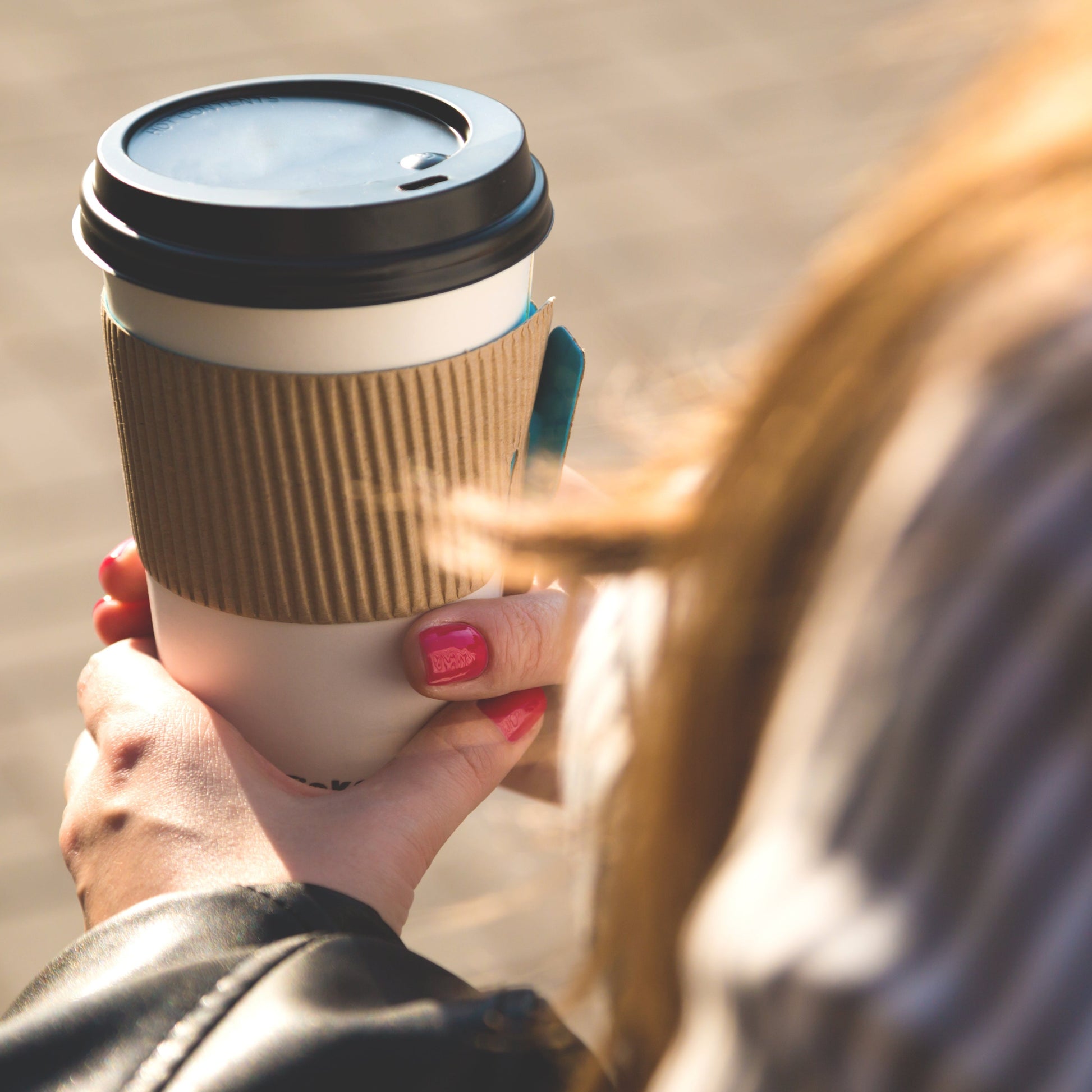 Woman holding hot beverage to go cup